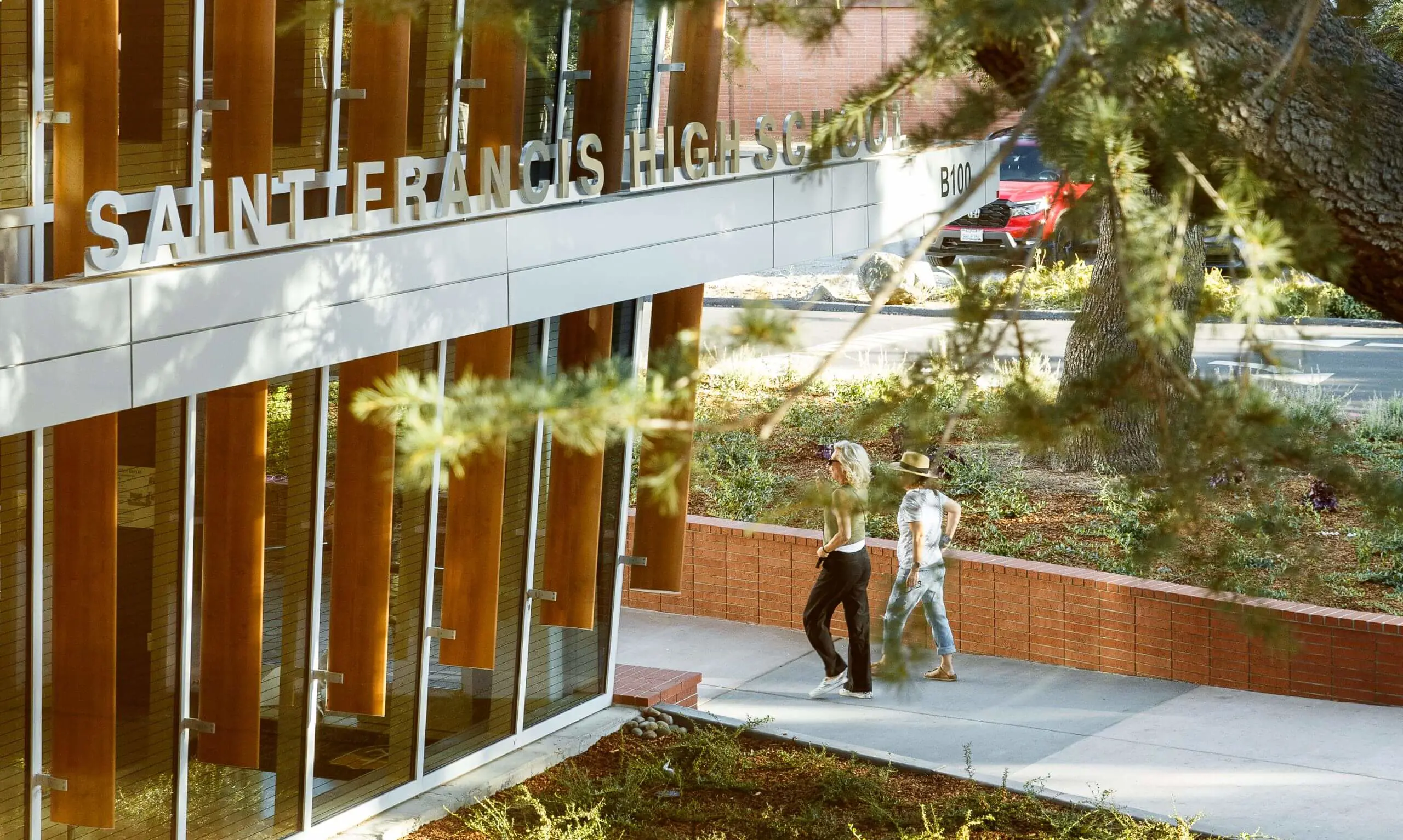 The front of the welcome center with a glass-facade building nestled among vibrant trees, blending nature with contemporary architecture.