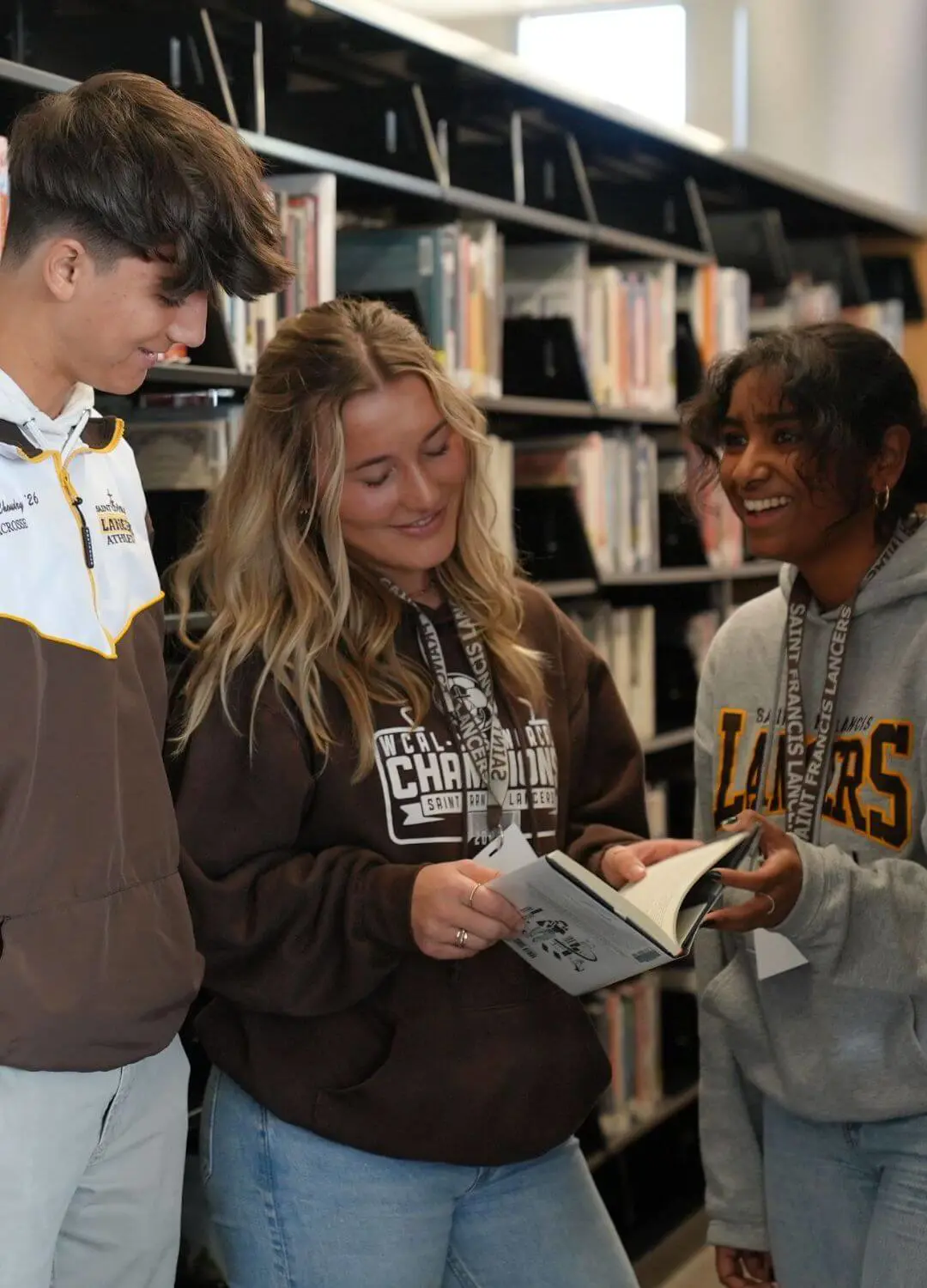 Students browsing books in a library, focused on their selections and surrounded by shelves of literature.