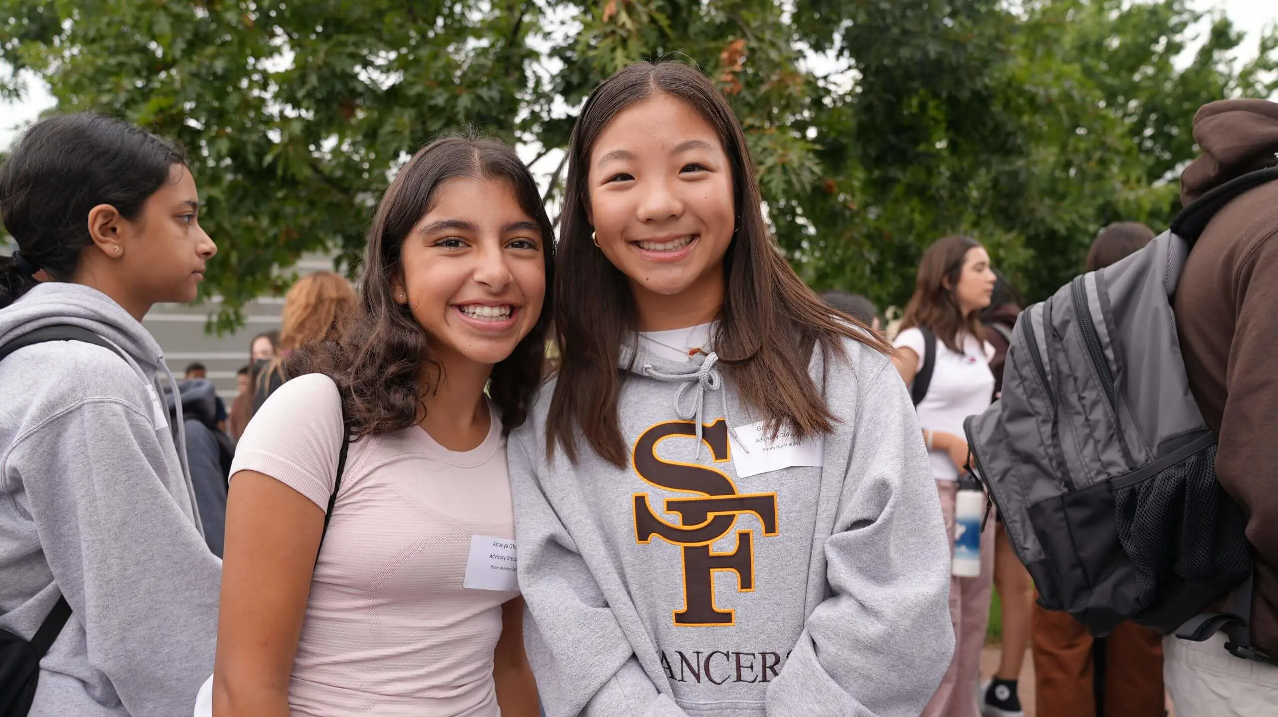 Saint Francis students wearing Lancer gear smiling at the photographer during an event.