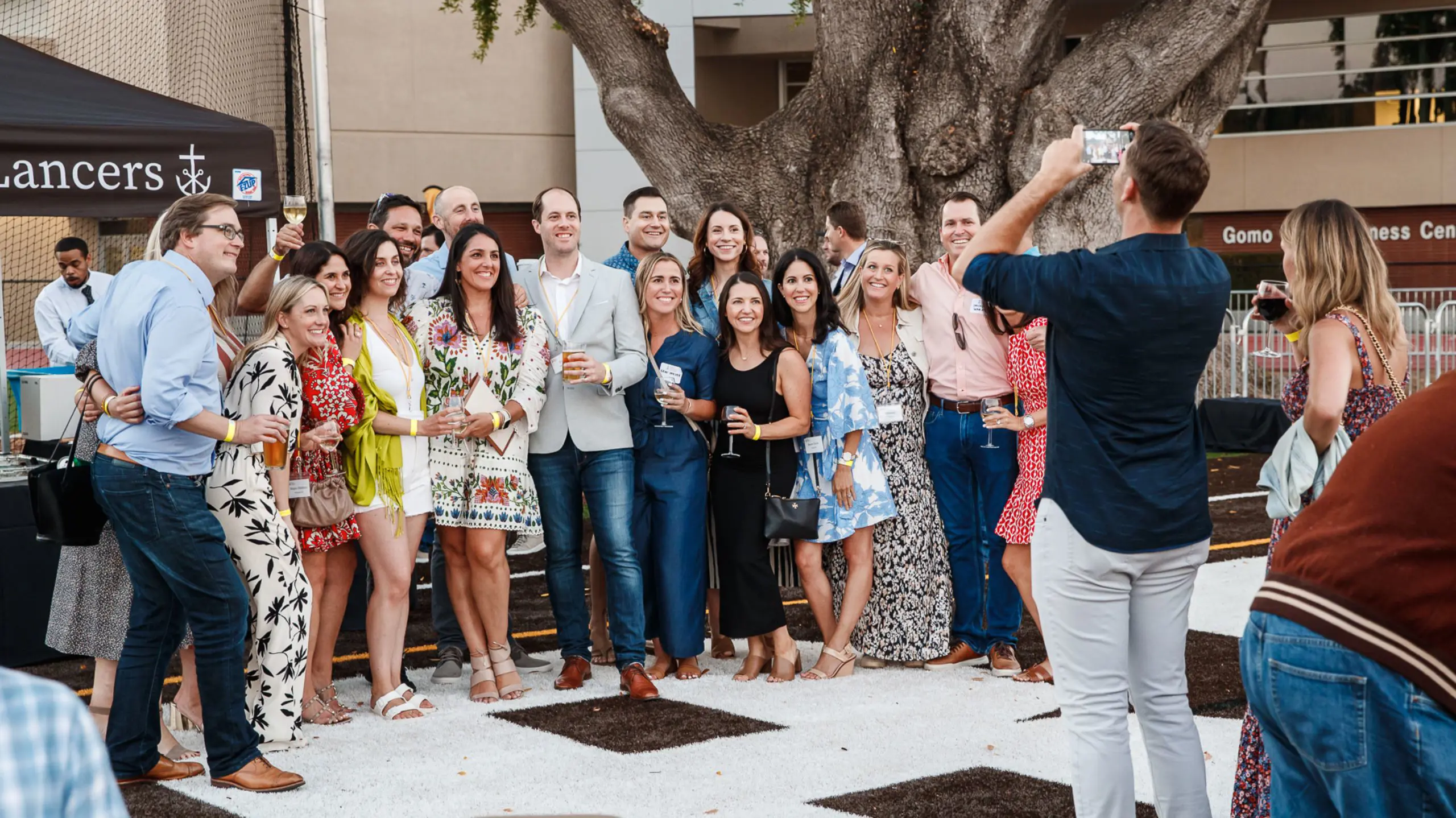 Alumni gathering for a photo under the Bay Tree at a class reunion.