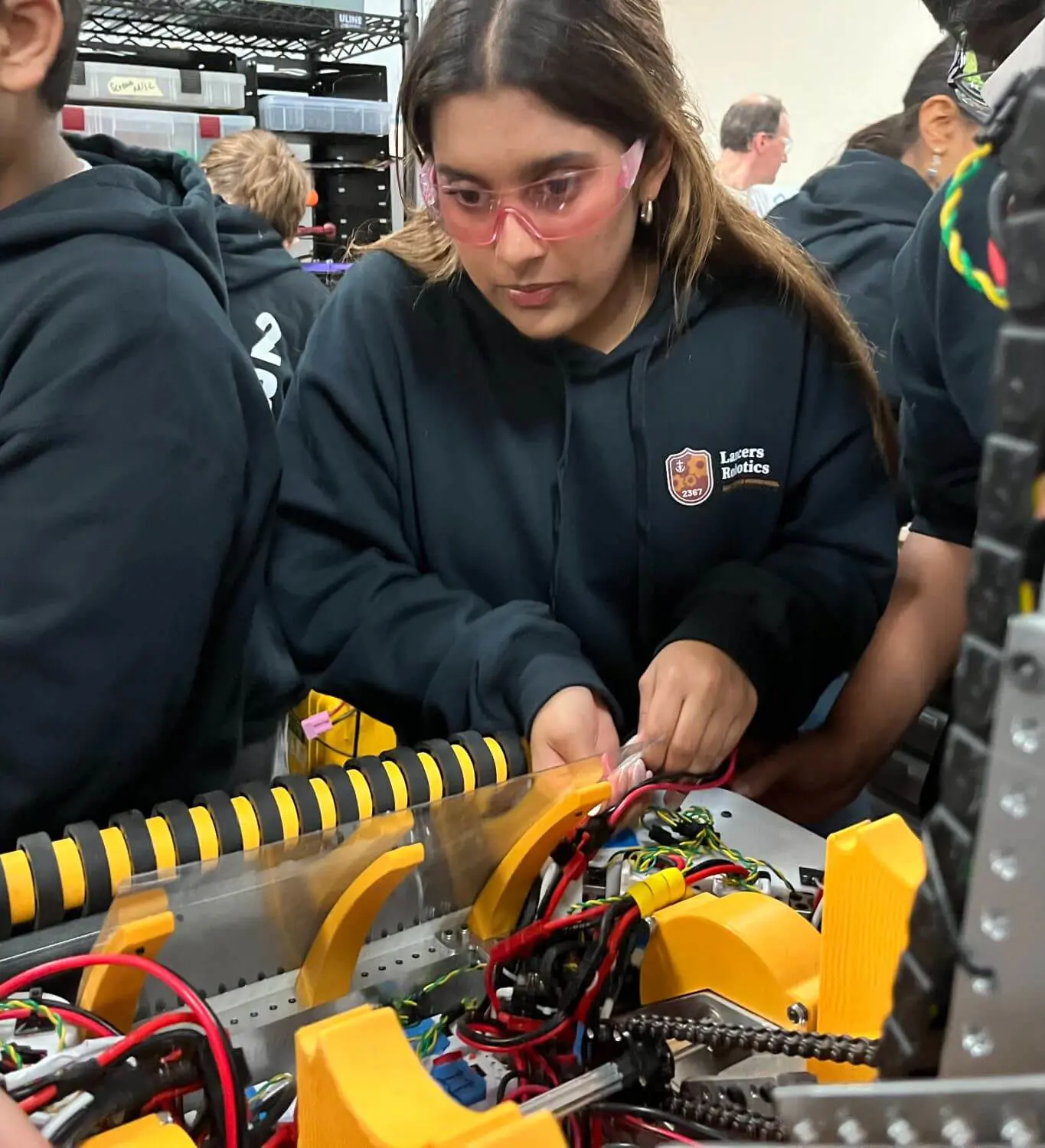 Students engaging each other while working on a robot.
