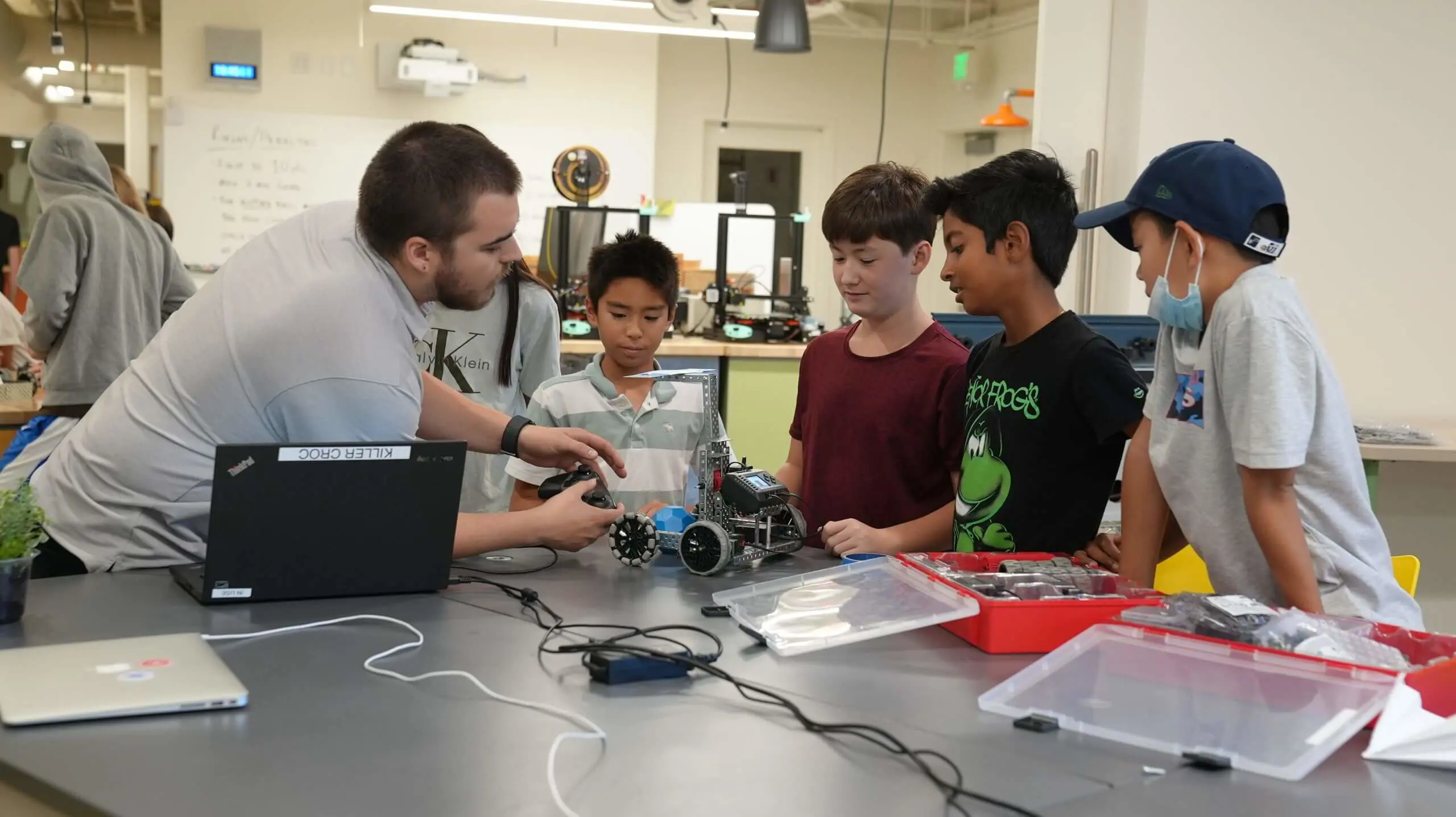 Camp Counselor working with four students on robotics in the Innovation Lab.