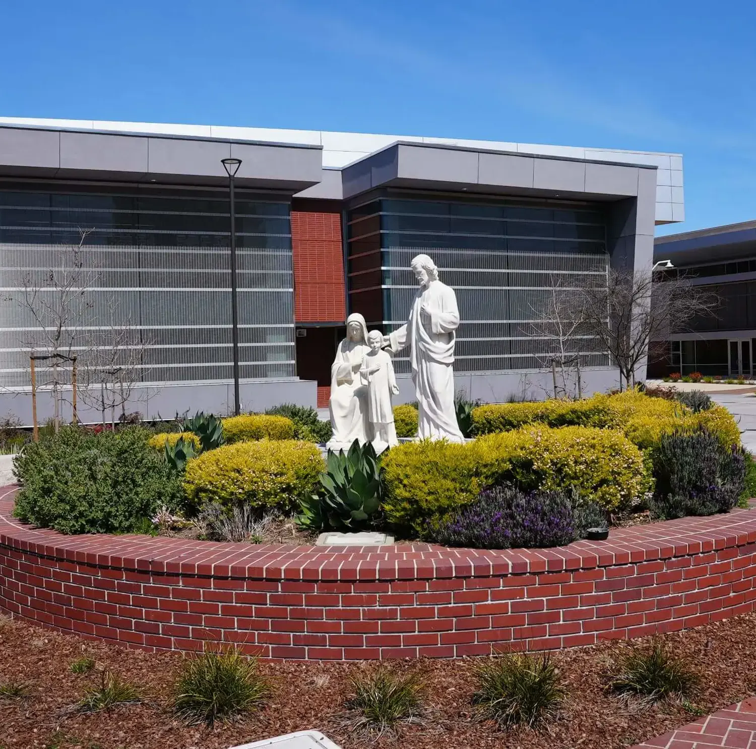 The Holy Family statue in the middle of the Quad depicts Jesus standing with Mary and Joseph, with the Eggers Innovation Center in the background.