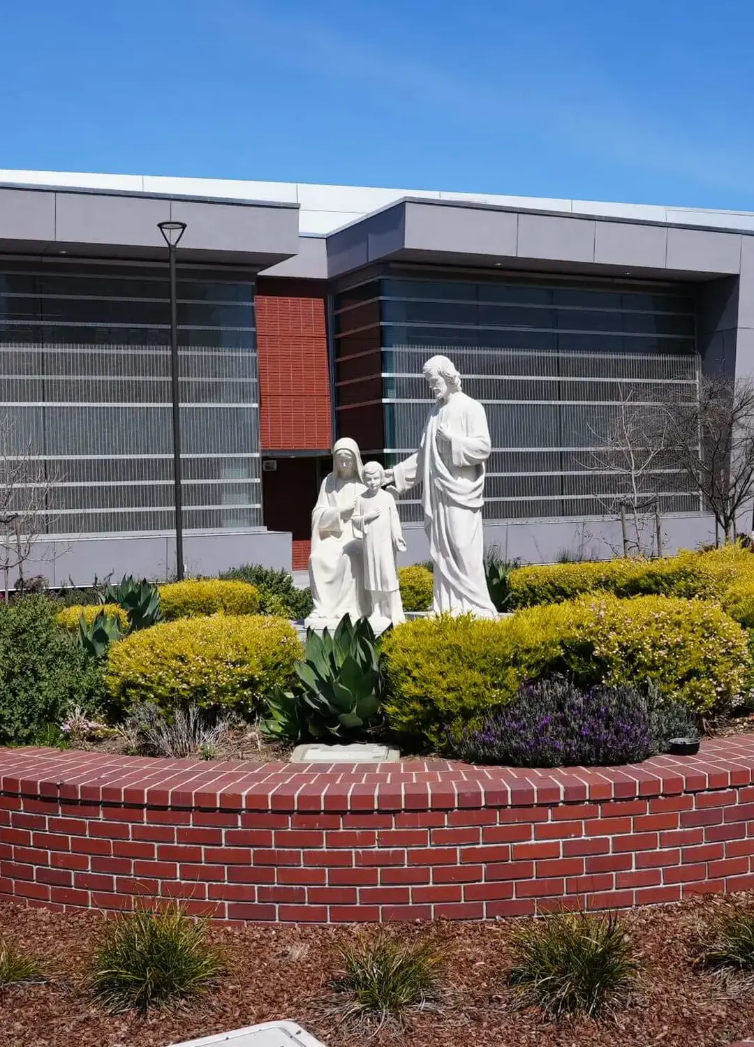 Alt The Holy Family statue in the middle of the Quad depicts Jesus standing with Mary and Joseph, with the Eggers Innovation Center in the background.