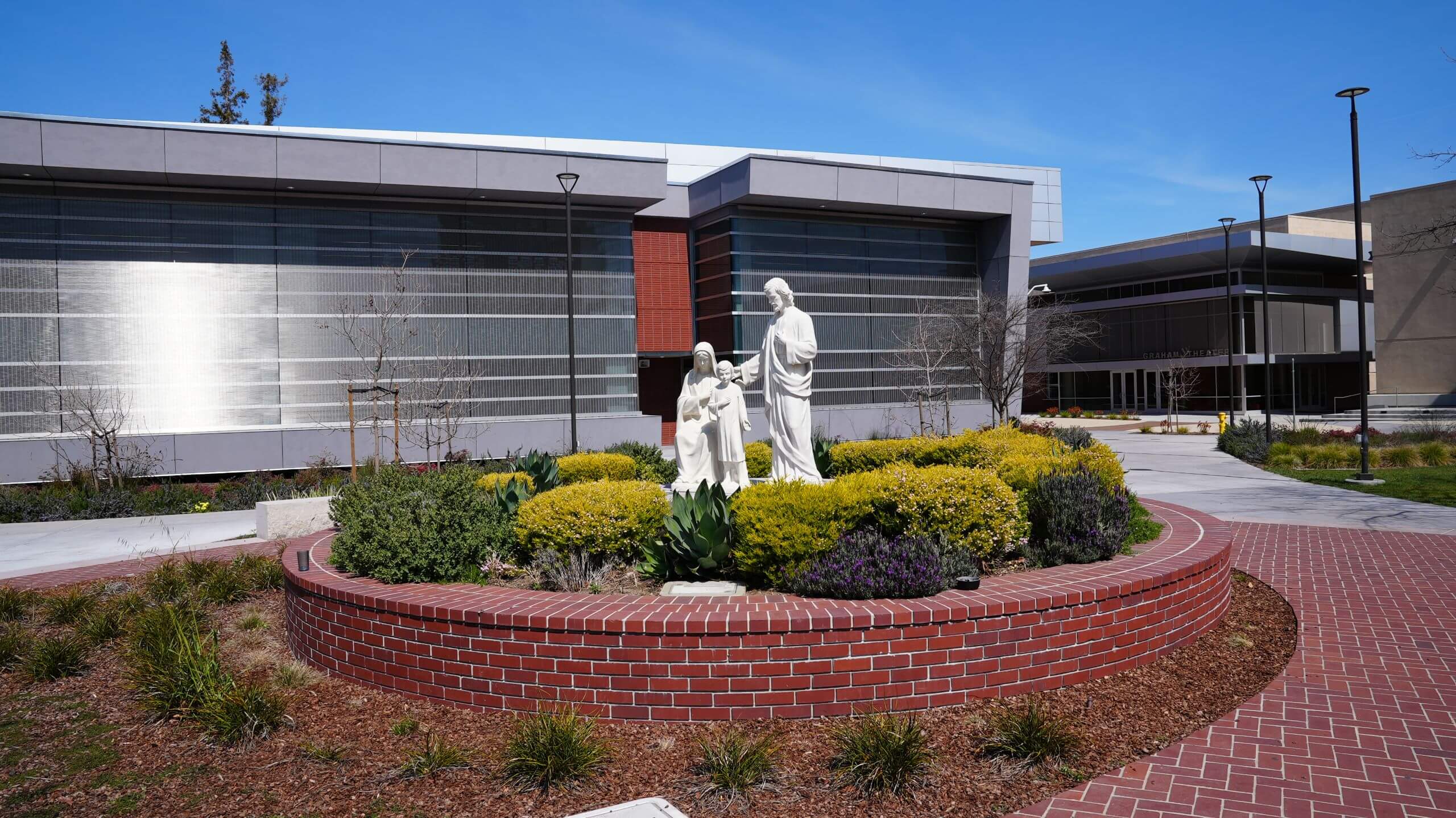 The Holy Family statue in the middle of the Quad depicts Jesus standing with Mary and Joseph, with the Eggers Innovation Center in the background.