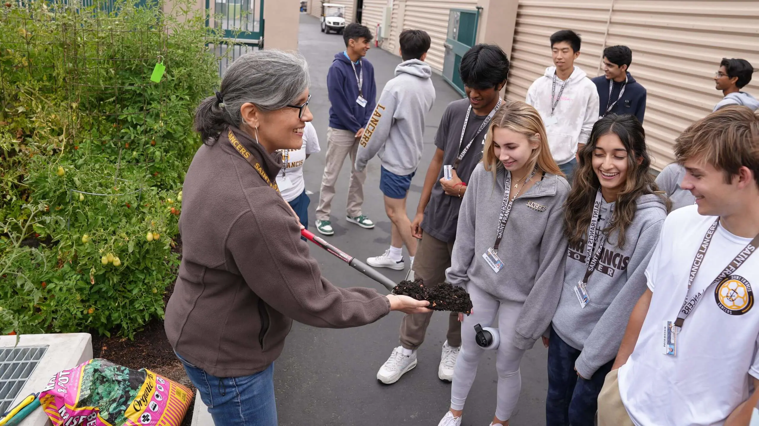 Students happily learn about ecology while working with the vegetable garden growing on campus.