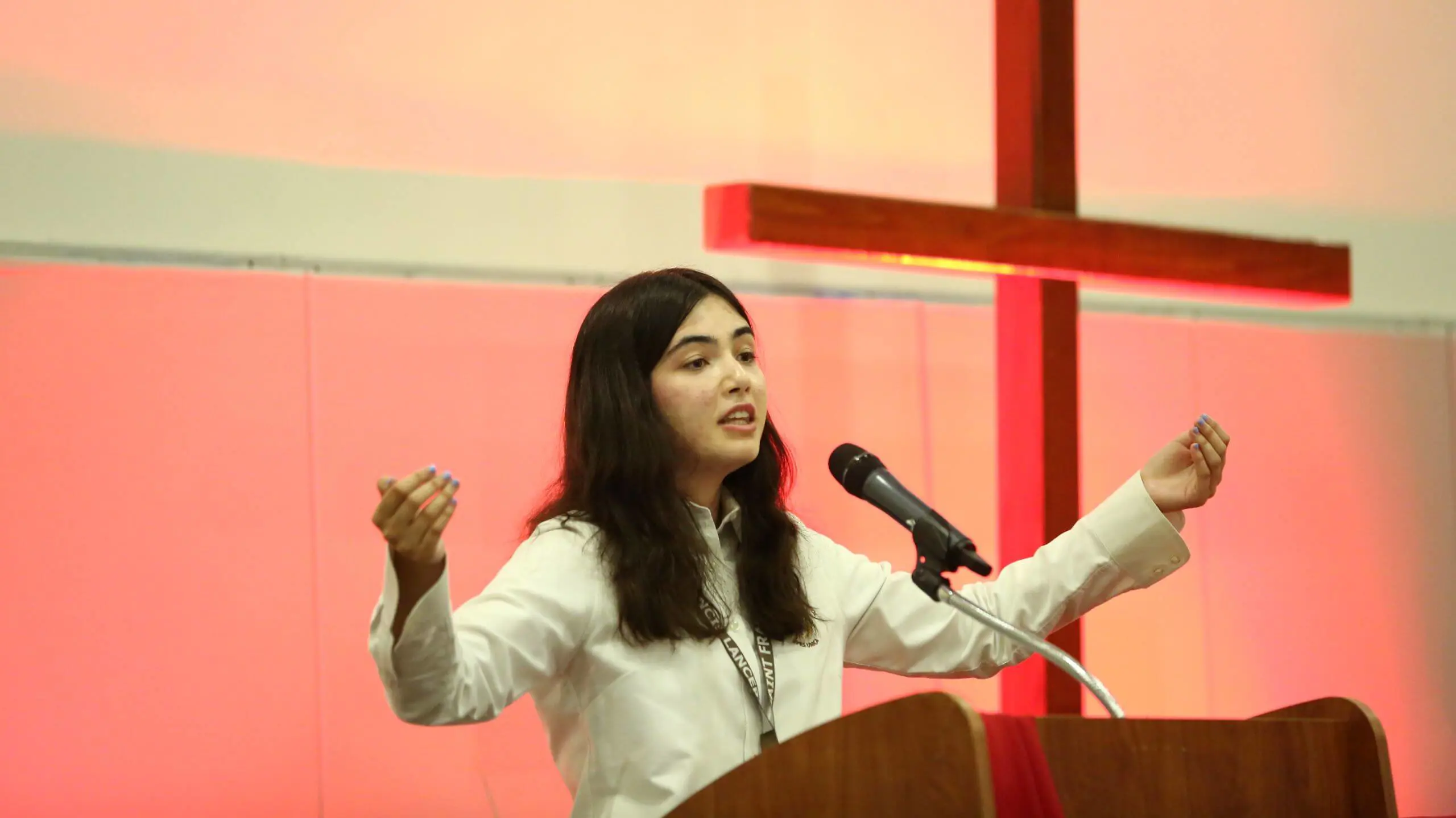A Student standing at the ambo leading the student body in prayer.