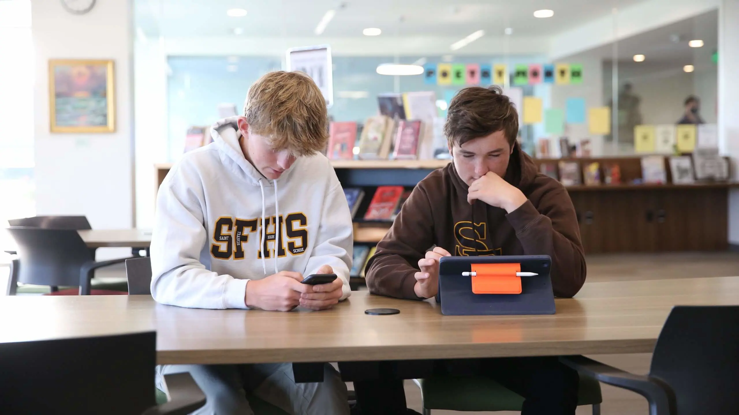 A student with a Saint Francis sweater working off a tablet.
