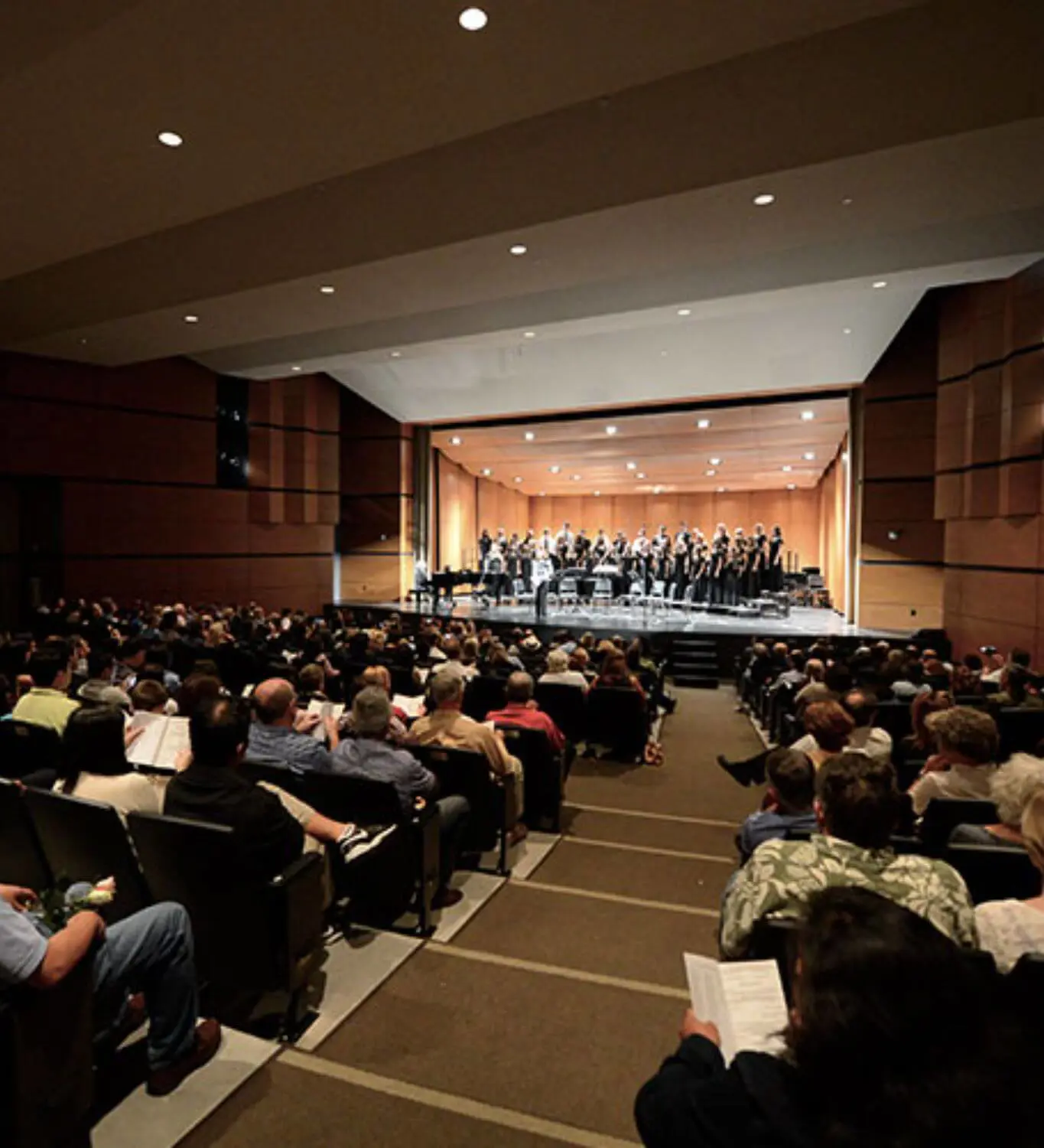 Audience watching a choir performance inside the Performing Arts Center.