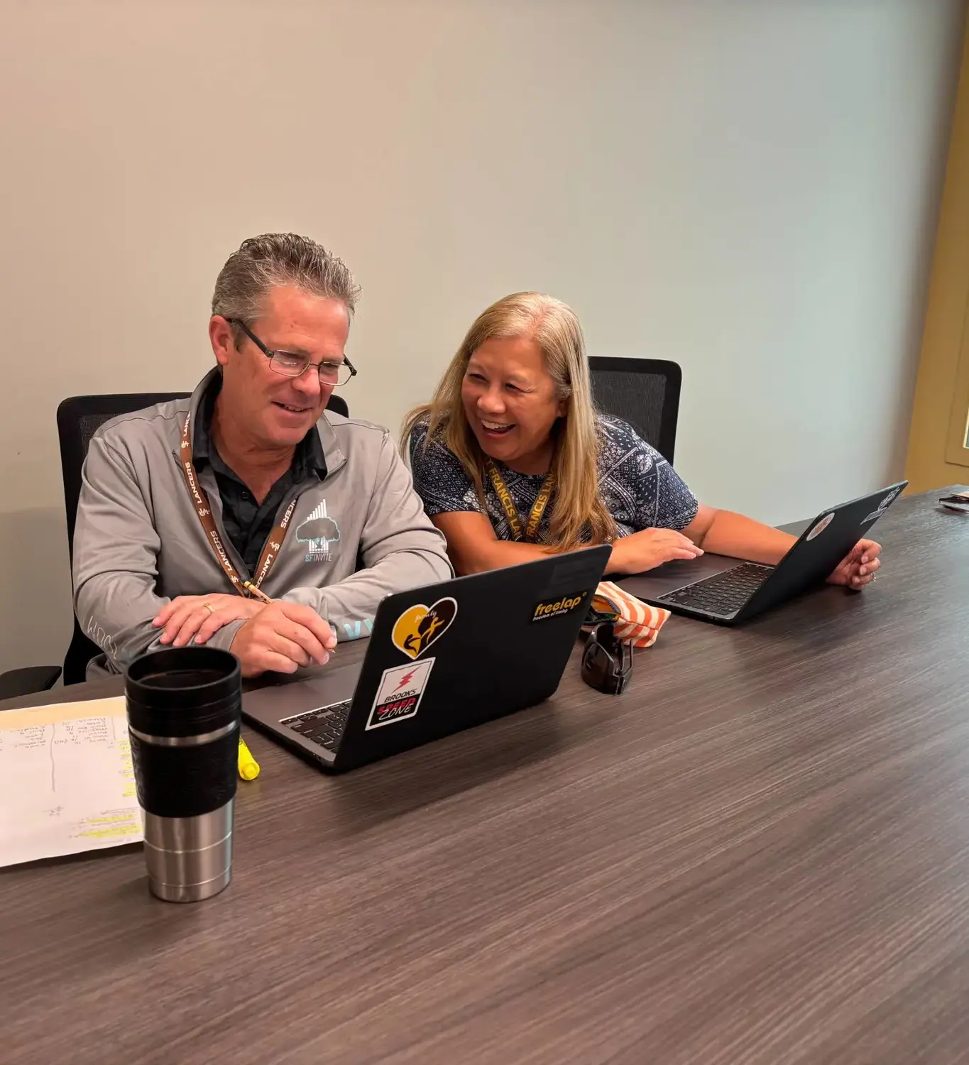 Colleagues seated at a table, each using a laptop, engaged in a collaborative work session