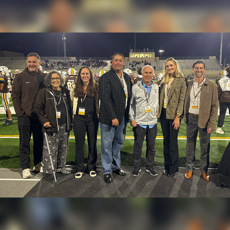 Hall of Fame Inductees pose on field during a football game