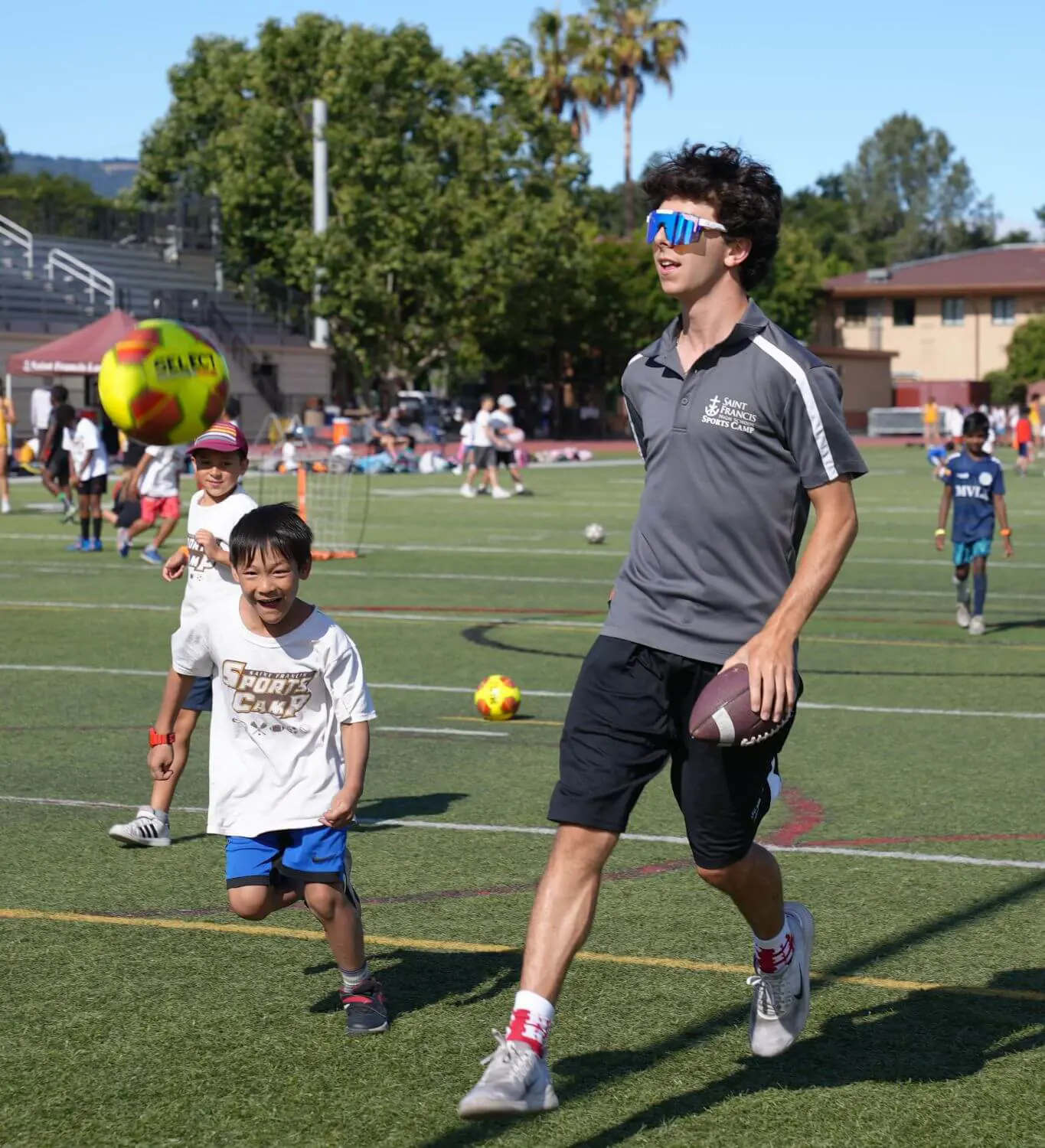 Camp counselor leading campers in a game of football.