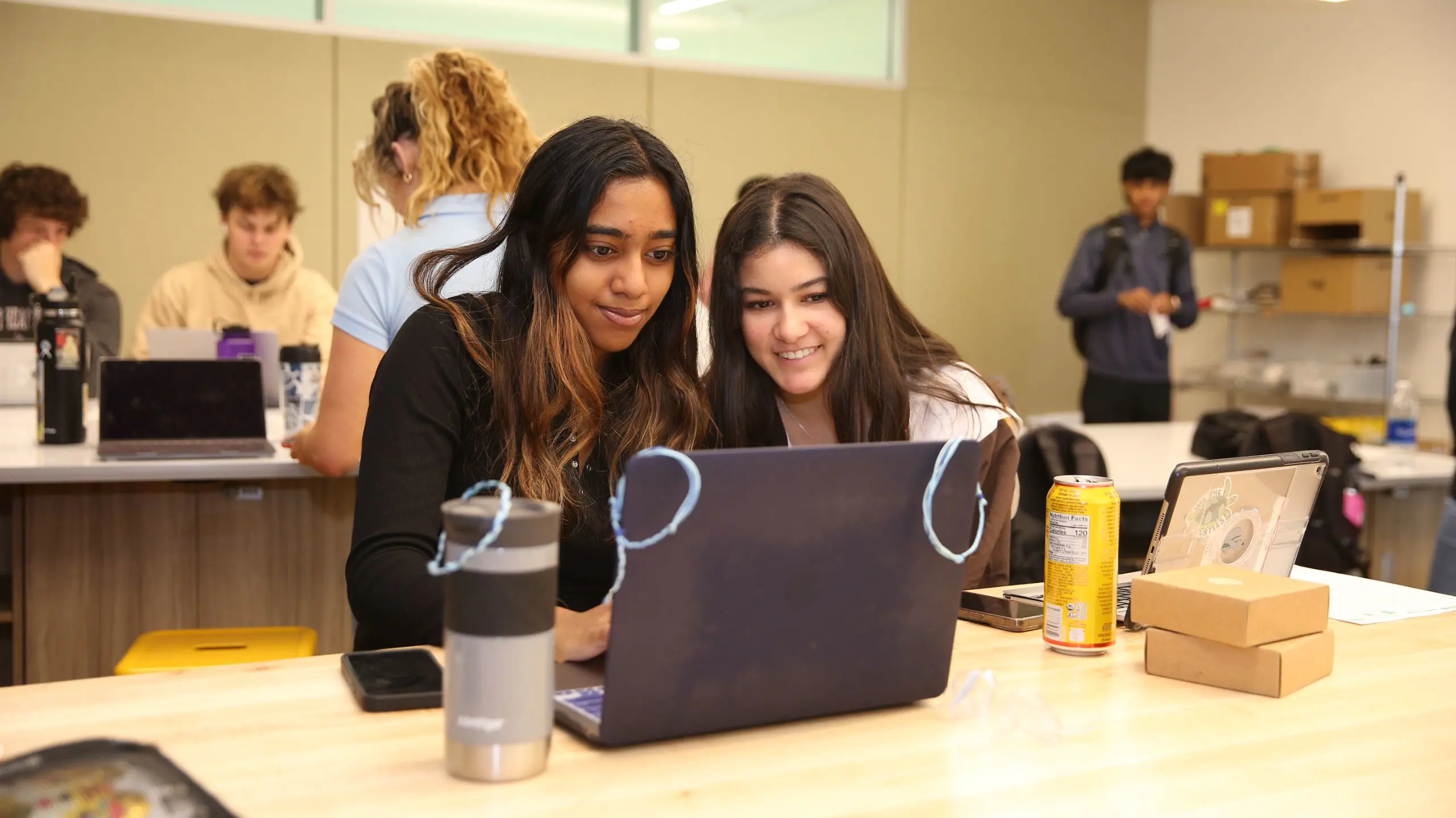 Two students working on a laptop in a lab.