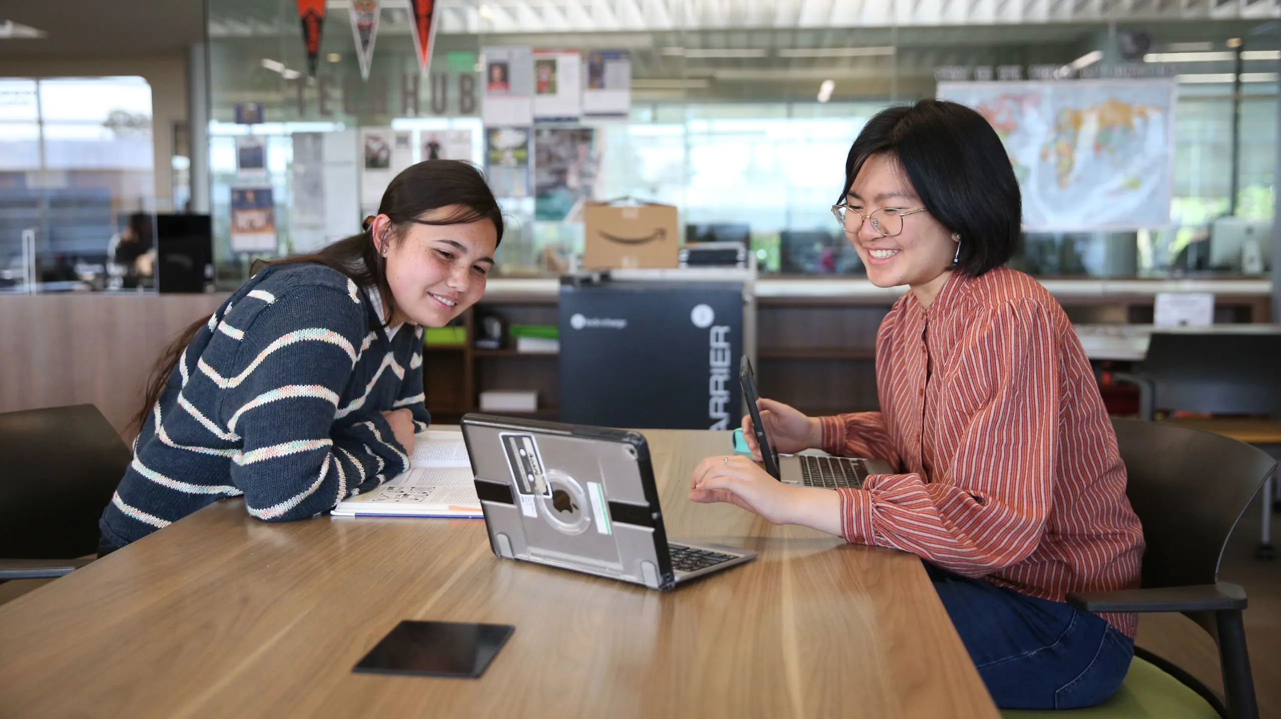 A student sitting at a table with a tutor, working on a subject.