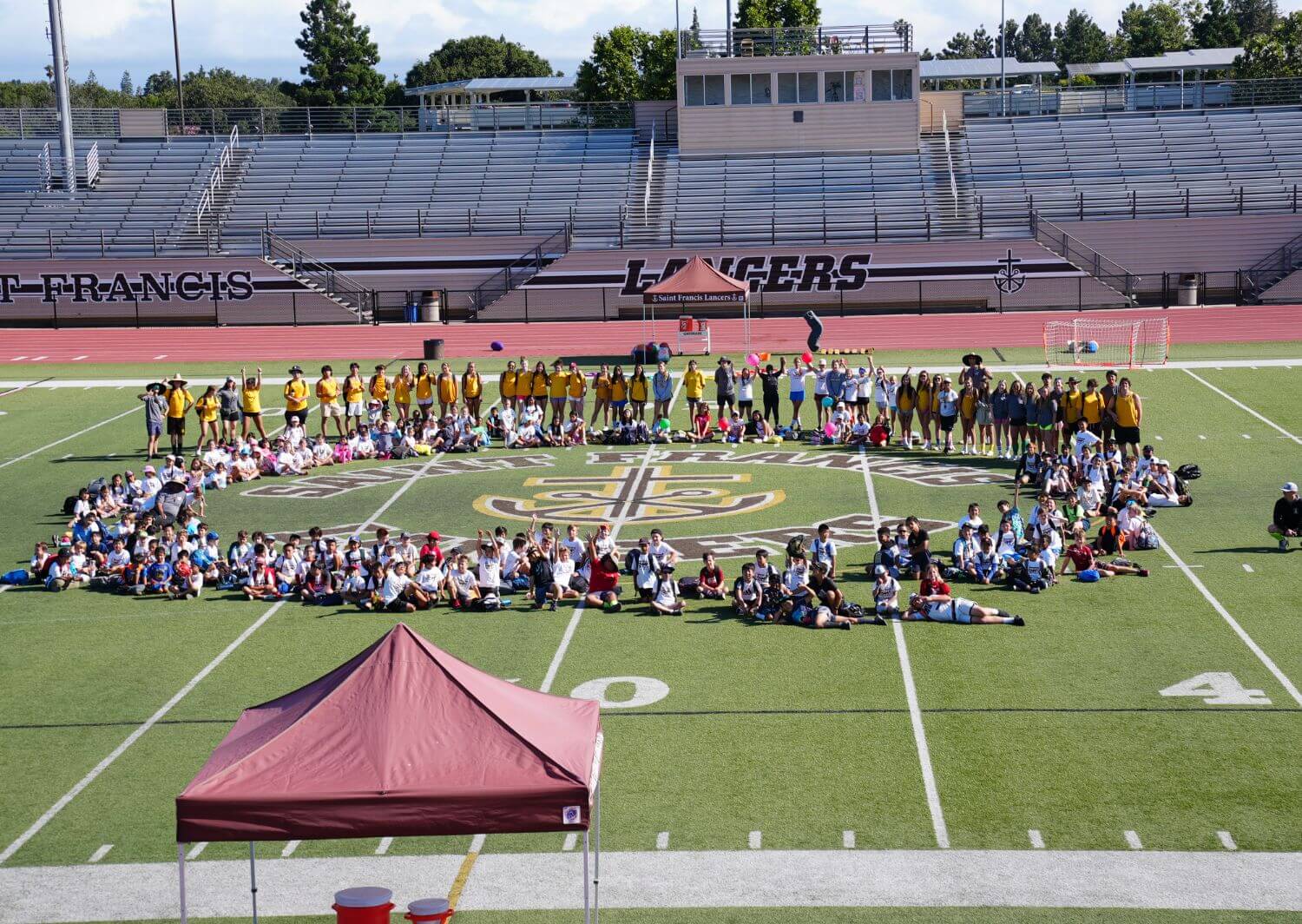 All youth campers and counselors surrounding the mid-field cross and anchor in the football stadium.
